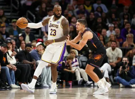 LeBron James (23) controla la pelota ante la marca de Grayson Allen en la victoria de Los Angeles Lakers sobre Phoenix Suns el 14 de diciembre de 2025 en partido de la temporada regular de la NBA jugado en Phoenix, Arizona