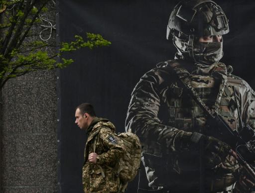 Un soldado ucraniano pasa junto a un cartel de reclutamiento en Kiev el 23 de abril de 2024.