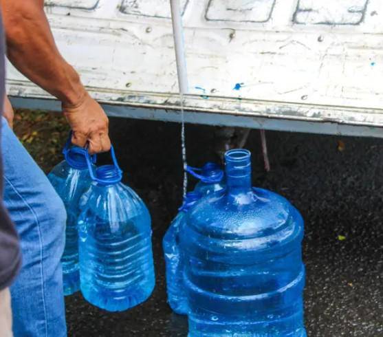 Cortesía | Una persona cargando agua en botellas.