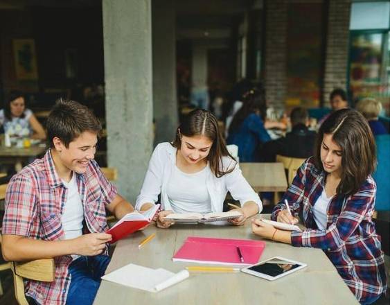 Magnific | Tres jóvenes estudiantes realizando sus tareas juntos en la Biblioteca de la universidad.