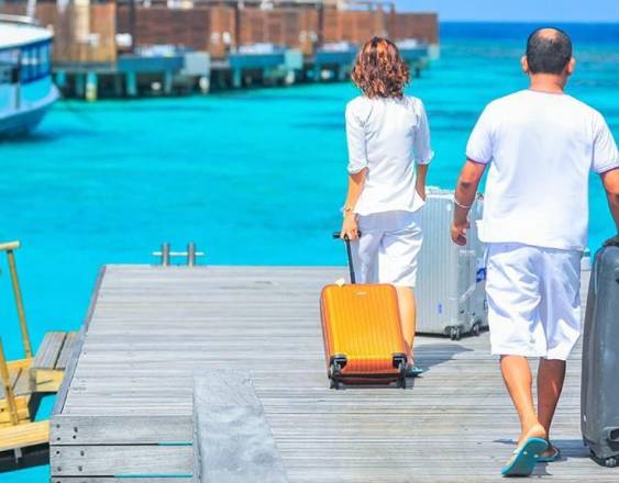 PEXELS | Dos turistas con sus maletas en un puerto.