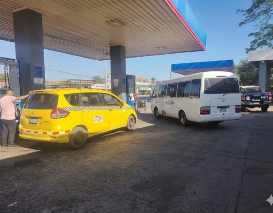 Policía/IA | Un taxi y un coaster en una estación de gasolina.
