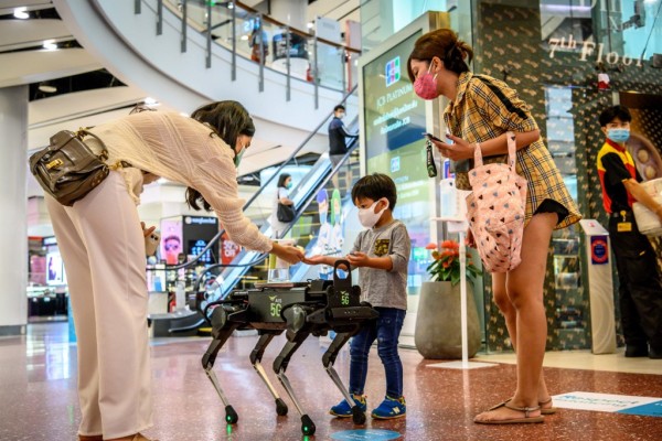 Un perro robot distribuye gel para las manos en un centro comercial en Bangkok