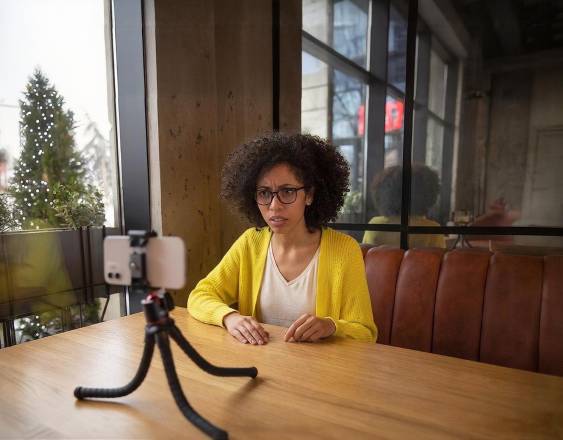 Magnific | Una mujer grabando un video en un restaurante usando su celular creando contenido para sus redes sociales.