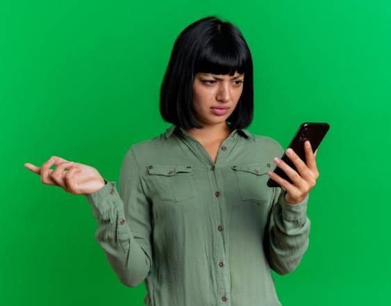 Magnific | Una mujer observa su celular sorprendida.