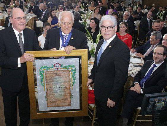 CoNEP | Darío Selles (centro) mientras era galardonado con la medalla Jorge M Arias.