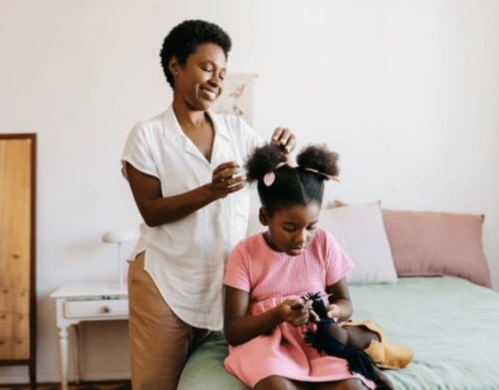 Freepik | Una madre peinando el cabello de su hija.