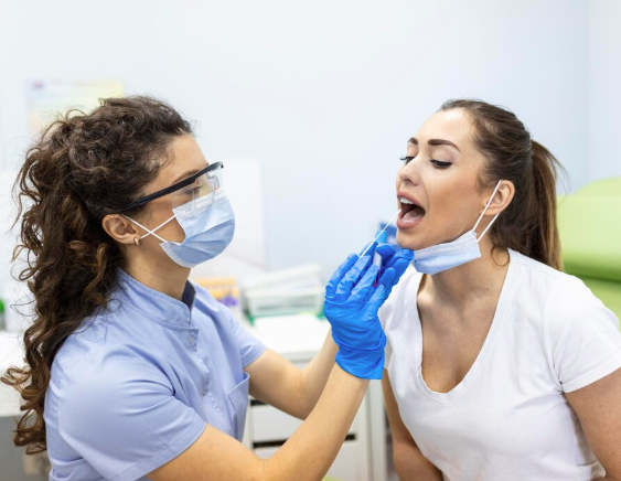 Magnific | Médico tomando una prueba de frotis de garganta de una paciente.