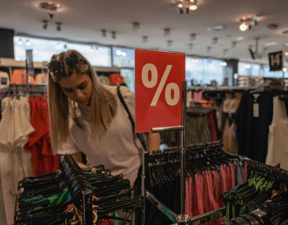 Pexels | Una mujer observa con detenimiento las diferentes prendas de vestir que se encuentran exhibidas con descuento dentro de una tienda.