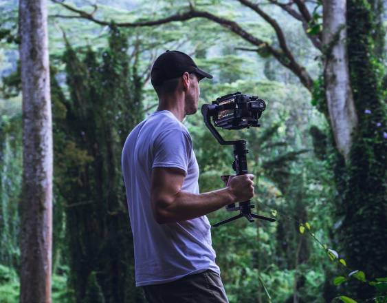 Pexels | Un hombre está con una cámara filmando en la selva.