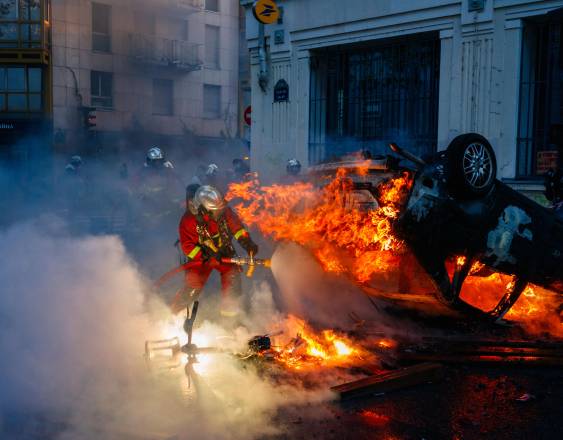 Firefighters extinguish a burning car along the