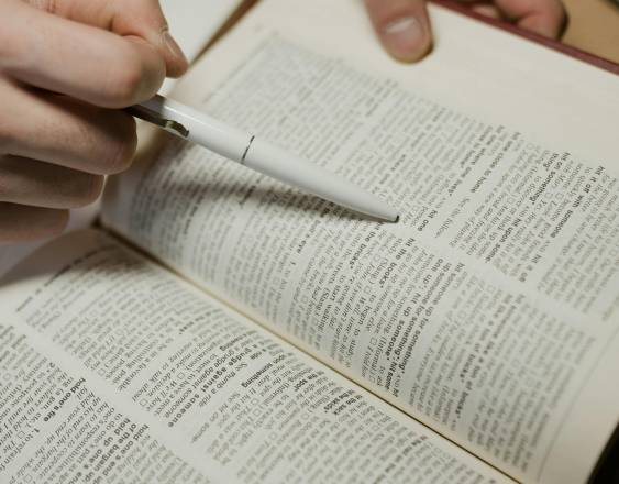 Pexels | Una persona busca definiciones en un diccionario de forma manual.