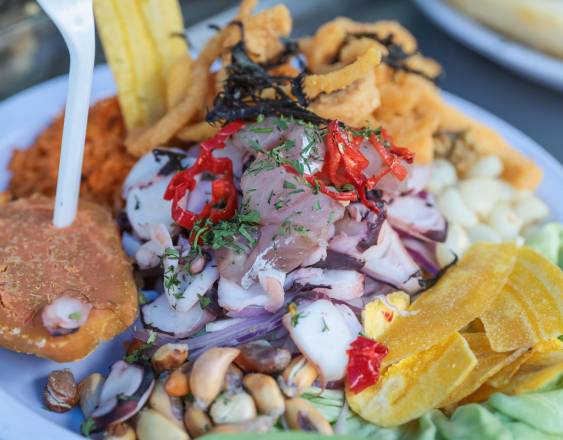 Un ceviche peruano tradicional con chifles (rodajas de plátano verde fritas) y chicharrones de calamar gigante fritos.
