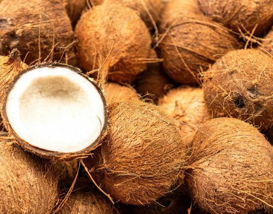 PEXELS | Varios cocos en el suelo. Uno de ellos a la mitad.