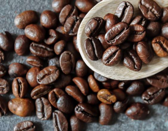 PEXELS | Granos de café sobre una mesa. Algunos están encima de una cuchara de madera.