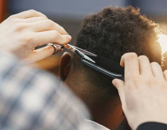 PEXELS | Un barbero estilizando un cabello afro.