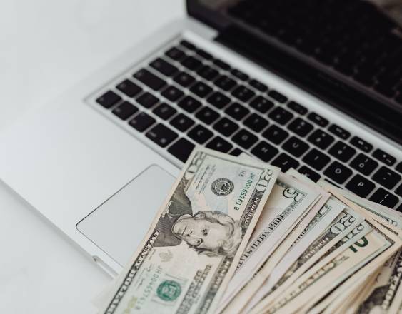 ML | Dinero en efectivo sobre una computadora portatil.