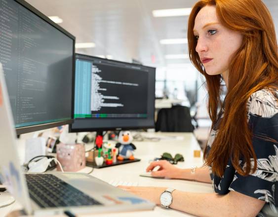 Pexels | Mujer trabajando en computadora con varios monitores.