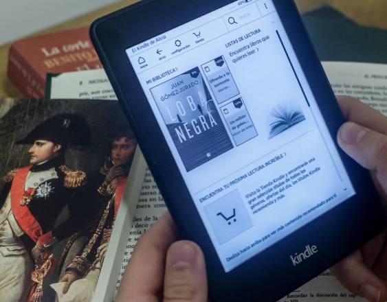 Una persona lee en un libro digital sobre libros en papel, a 5 de abril de 2024, en Madrid (España).