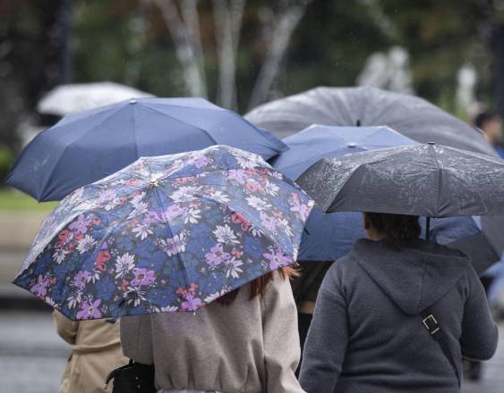 AFP | Personas con paraguas caminan bajo la lluvia.