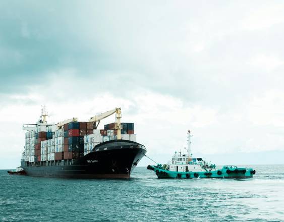 PEXELS | Un buque portacontenedores y un remolcador.