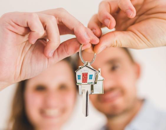 Pexels | Una pareja, muy sonriente, sostiene las llaves con un colgante en forma de casa.