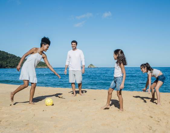 Freepik | Una familia disfrutando del verano jugando fútbol en la playa.