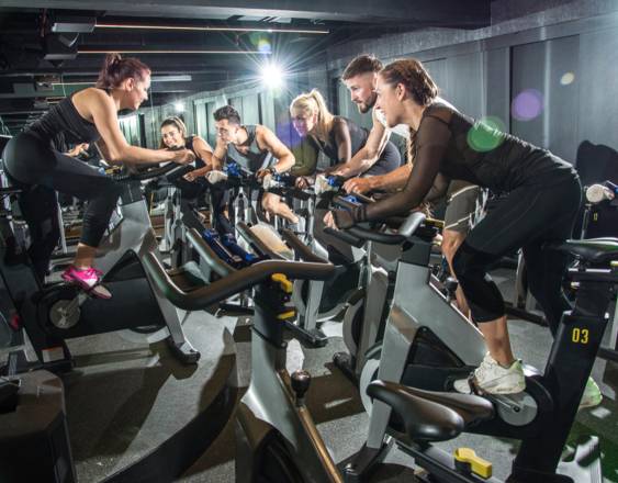 Cortesía | Un grupo de personas en un gimnasio en una sesión de bicicleta estática.