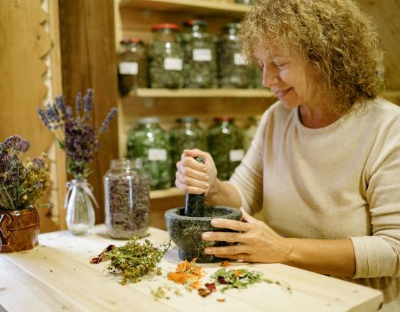 Pexels | Una mujer en su casa preparando un remedio con varios tipos de plantas.
