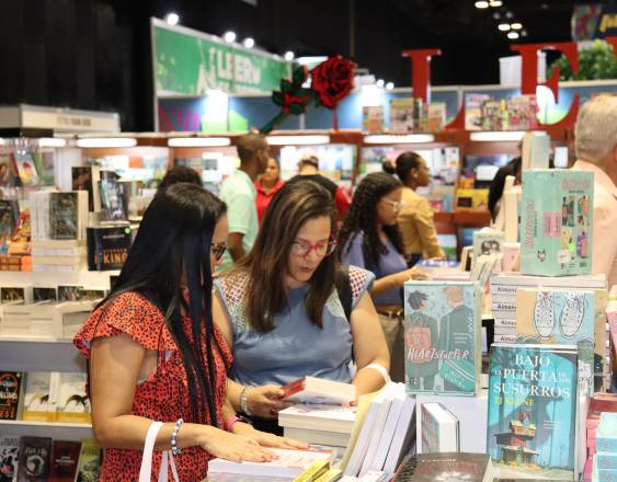 ML | Asistentes a la Feria Internacional del Libro observan algunas obras en las mesas con títulos y temáticas variadas.