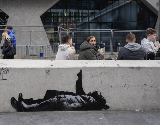 AFP | Los peatones pasan junto a un mural en el costado de una pared, que según los medios locales fue creado por el artista callejero Banksy.