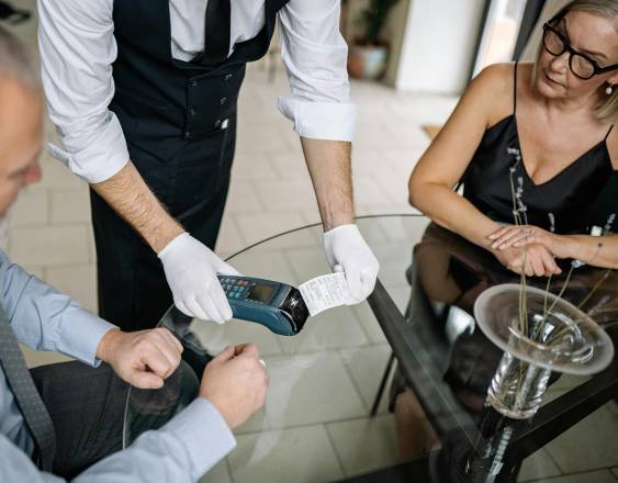 PEXELS | Dos personas jubiladas realizando el pago de una comida en un restaurante.