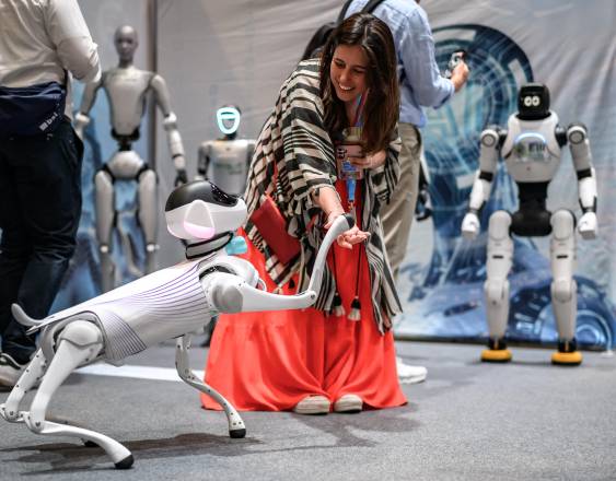 AFP | Un visitante interactúa con un perro robot.