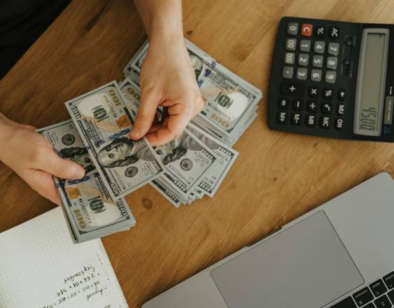 Pexels | Una perosna cotando billetes de cien balboas.