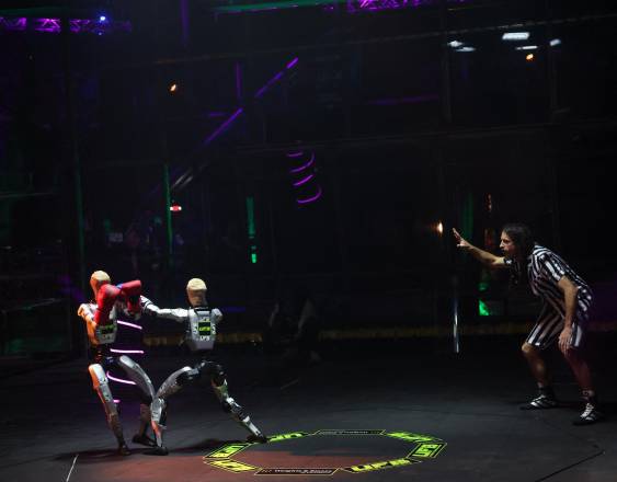 AFP | Un árbitro señala un punto mientras robots con guantes de boxeo intercambian golpes durante la competición Ultimate Fighting Bots (UFB) en el BattleBots Arena.
