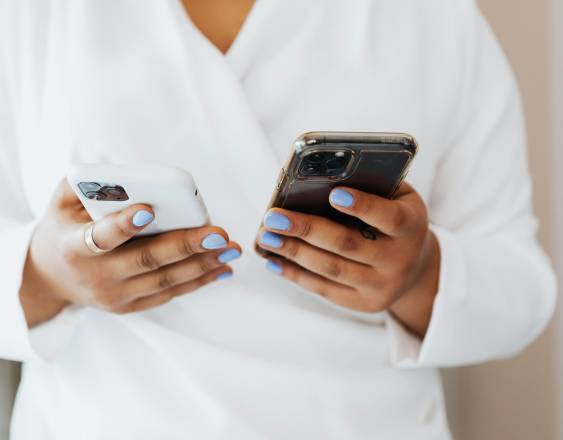 PEXELS | Una mujer utiliza dos celulares para verificar el funcionamiento de los mismos.