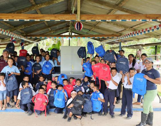 ML | Estudiantes recibiendo bolsas con útiles escolares.