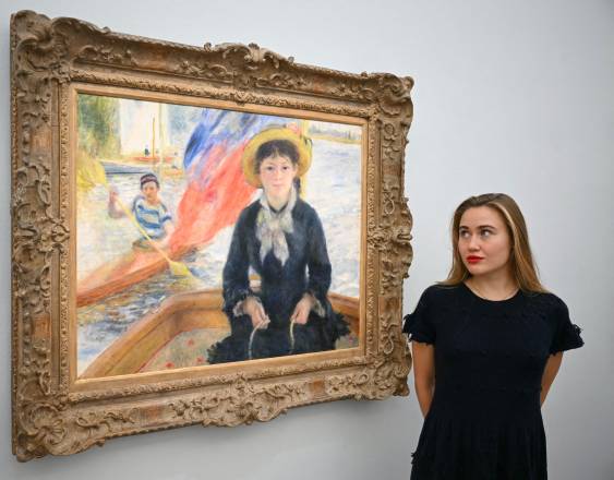 AFP | Un miembro del personal posa junto a la obra “En Canot” (Jeune fille à la barque), del artista francés Pierre-Auguste Renoir.