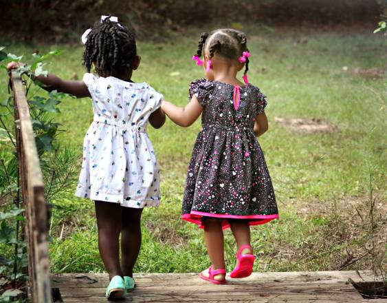 PEXELS | Dos niñas jugando tomadas de la mano.