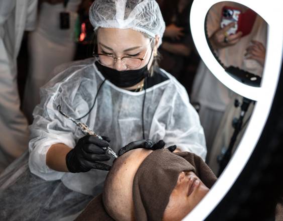 Un especialista en tatuajes de cuero cabelludo realizando una demostración durante un concurso de tatuajes.
