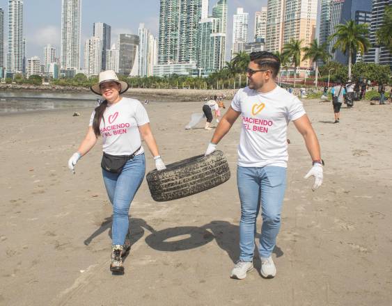 Cortesía | Dos personas cargan una llanta en una limpieza de playa.