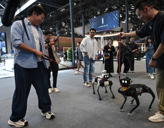 AFP | Personas paseaban con sus perros robot en el Salón del Automóvil de Pekín.