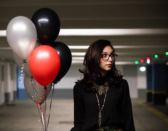 Pixabay | Un racimo de globos con gas y una joven al lado.