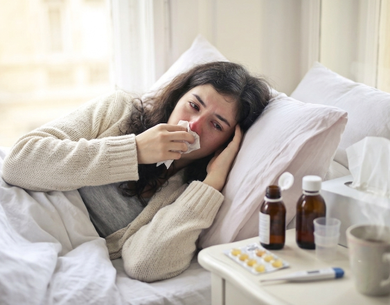 Generada con IA | Una mujer acostada en la cama con resfriado y Tomando Medicinas.