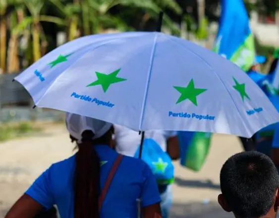 ML | Una persona con un paraguas que tiene la bandera del PP.