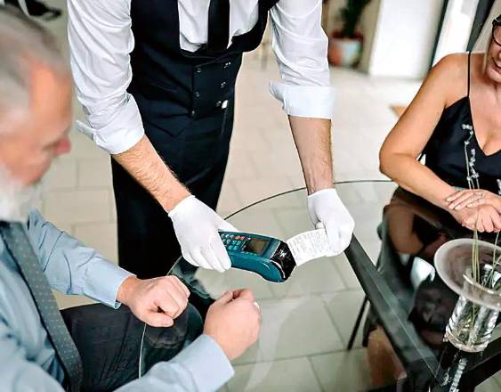 PEXELS | Dos personas jubiladas realizando el pago de lo consumido en un restaurante.