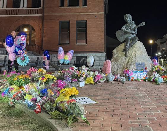 La estatua de bronce de la cantante y compositora estadounidense Dolly Parton aparece rodeada de flores y globos colocados por sus seguidores frente al Palacio de Justicia del condado de Sevier.