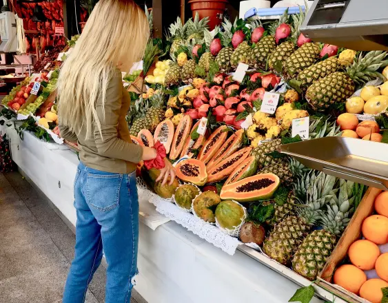 Pexels | Una mujer visitando el área de mercado en la feria y comprando papaya.