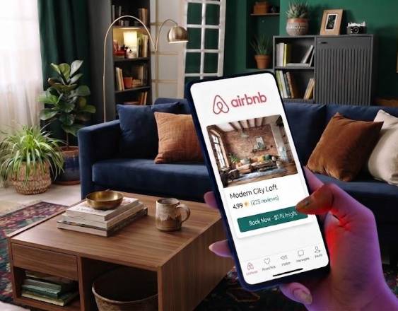 ML | Una persona revisando en un celular la aplicación de Airbnb y consulta opciones de alojamiento.