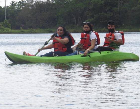 Travelandliving | Tres personas realizando kayak en un lago.
